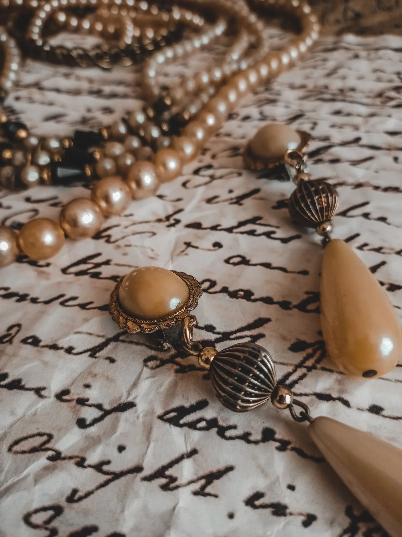 An inherited pearl necklace and a pair of drop earrings laid out on an old handwritten letter.