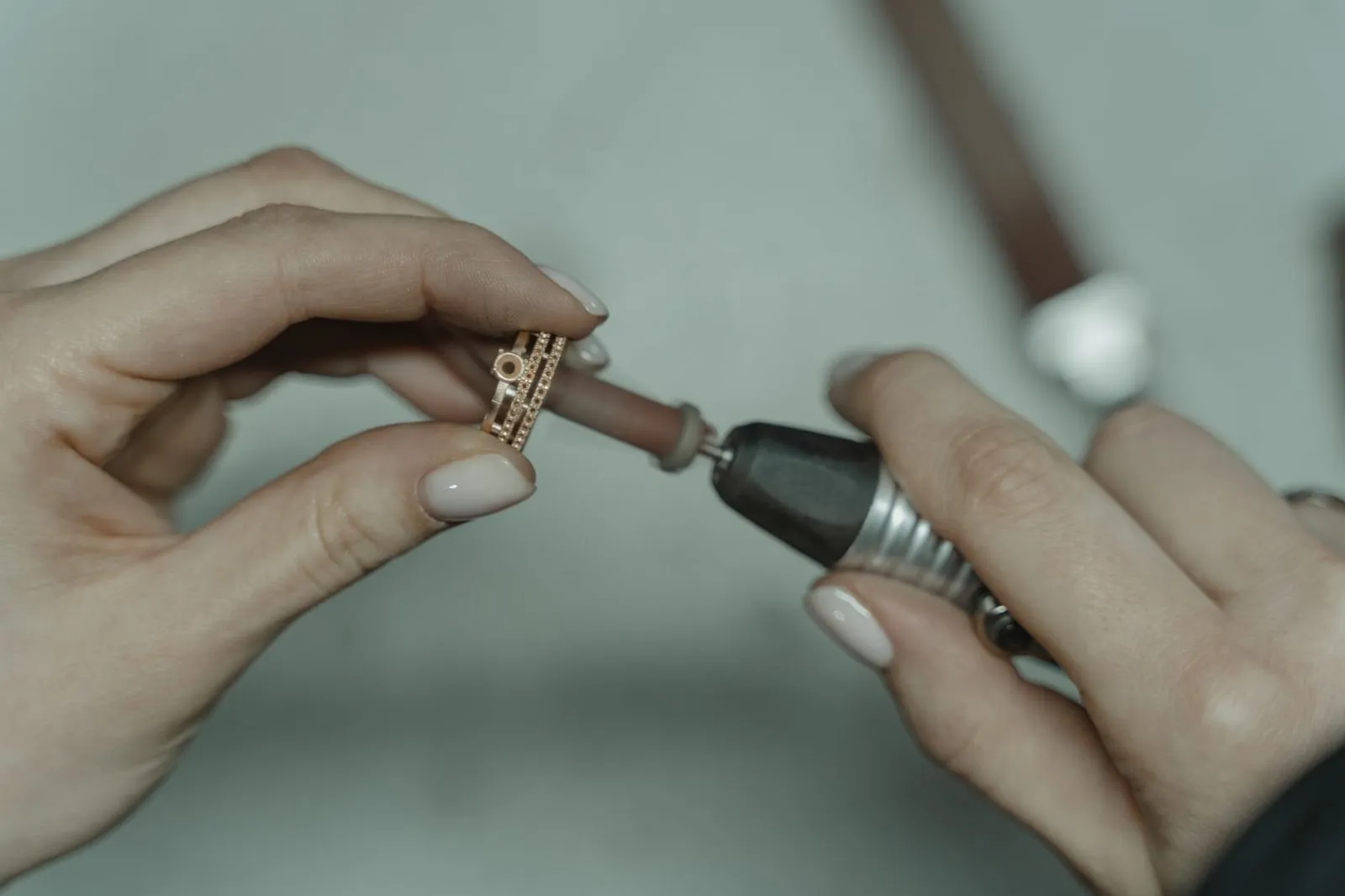 A rotary tool polishing a band held between finger and thumb.