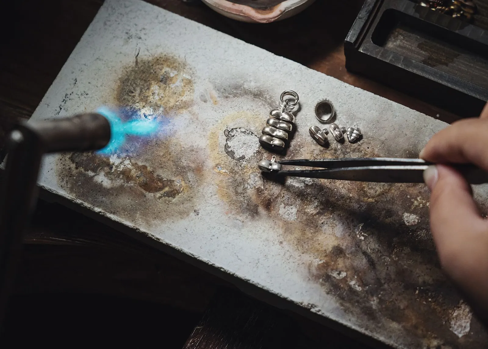 A torch flame playing over silver rings on a soldering block.